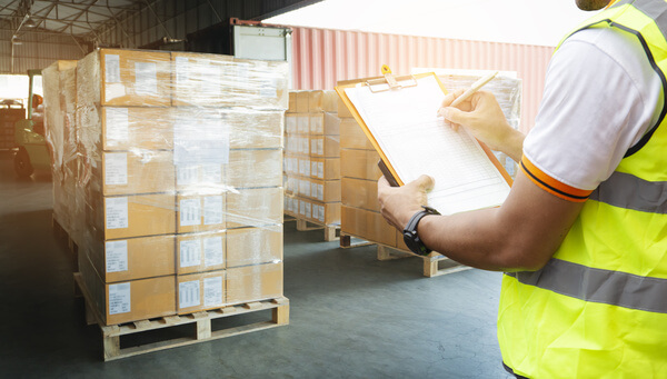 A warehouse worker marking off a checkboard while standing on a warehouse loading dock