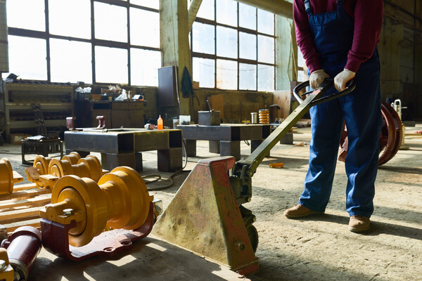 A pallet jack user pumping the handle to lift the forks