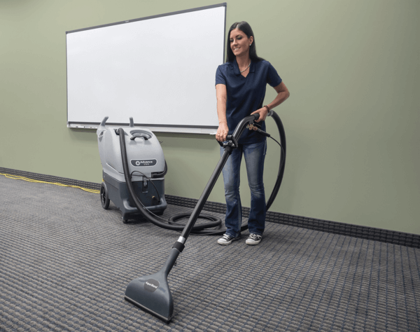 A worker using an Advance ET610 carpet scrubber to clean an office floor
