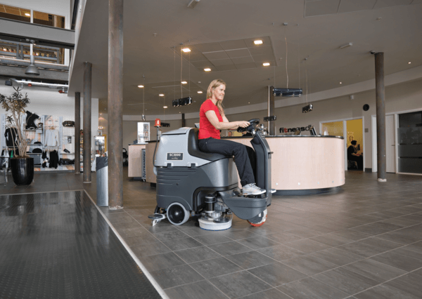 A worker using an Advance SC3000 rider floor scrubber to clean a hotel lobby