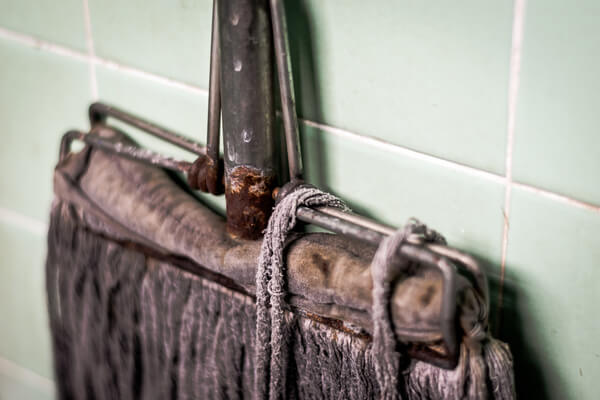 A dirty mop hanging from a wall