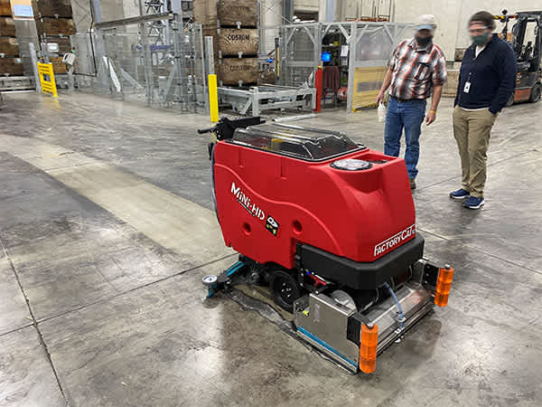 A Factory Cat Mini-HD walk-behind floor scrubber in a manufacturing facility