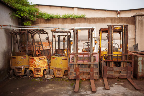 A row of rusted and worn forklifts