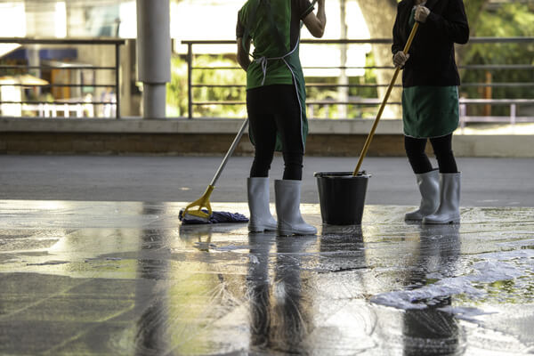 Two workers using mops and a bucket to clean a floor