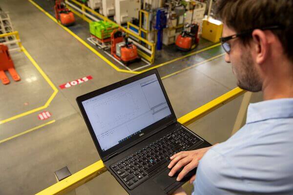 A worker using a laptop to monitor warehouse operations