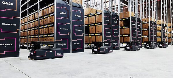 A line of AMRs traveling past pallet racking