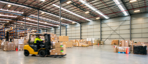 A forklift driving with a pallet inside a warehouse