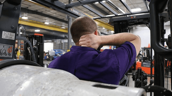 A forklift operator grabbing their neck in discomfort