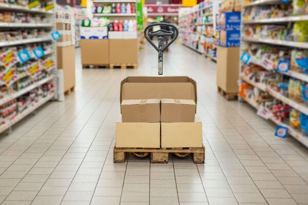 A pallet jack with a pallet on in it a supermarket aisle