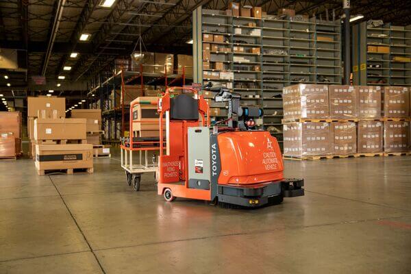 A Toyota AGV tow tractor towing a cart