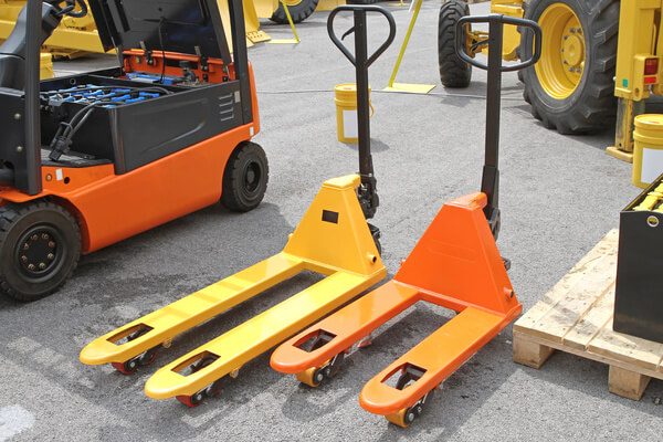 A standard length pallet jack next to a short pallet jack