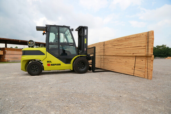 A CLARK internal combustion forklift lifting stacks of framing lumber