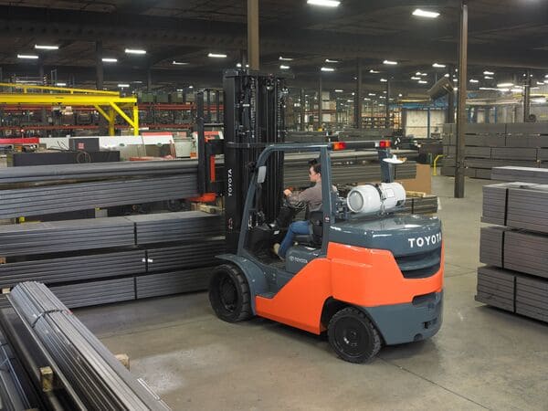 A Toyota large capacity forklift lifting a stack of steel sheets