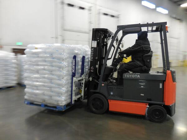 A Toyota forklift transporting pallets of ice in a warehouse