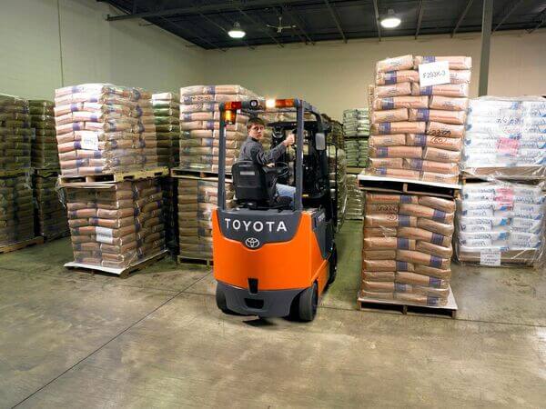 A forklift operator backing up in a warehouse