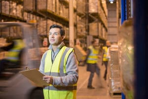 Male worker with clipboard in distribution warehouse