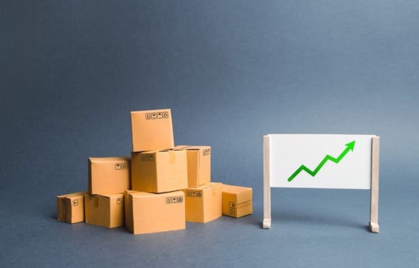 A chart with an arrow pointing up next to a pile of cardboard boxes