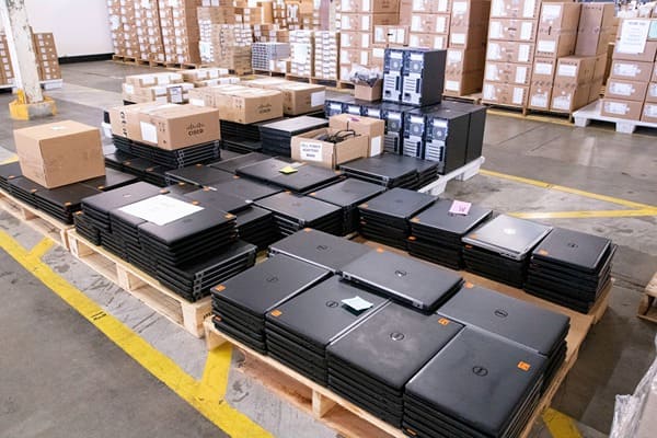 Stacks of laptops on pallets in a warehouse