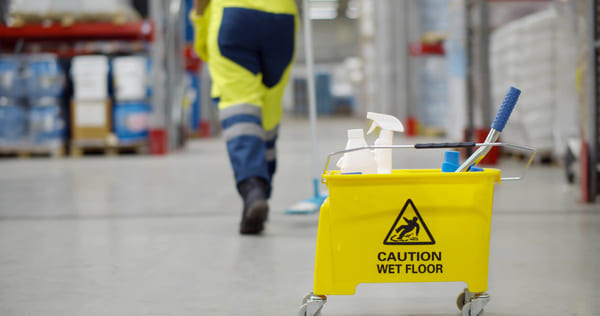 A warehouse worker talking away from a mop bucket