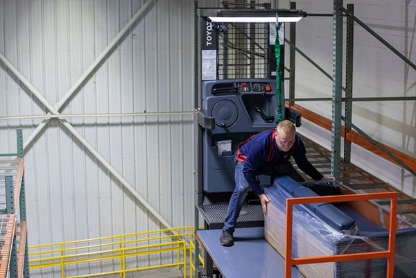 An order picker operator moving a couch onto pallet racking