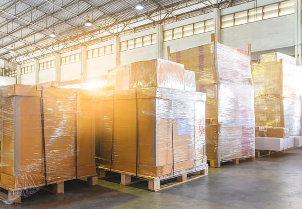 A group of pallets with items stacked in a pyramid shape in a warehouse