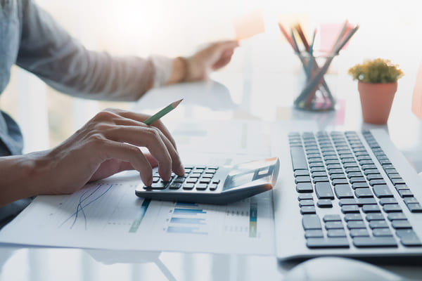 A person typing on a calculator on a desk