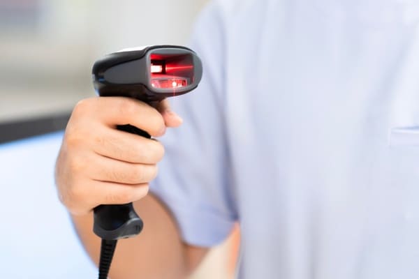A person holding a handheld RF scanner with a red light projecting out