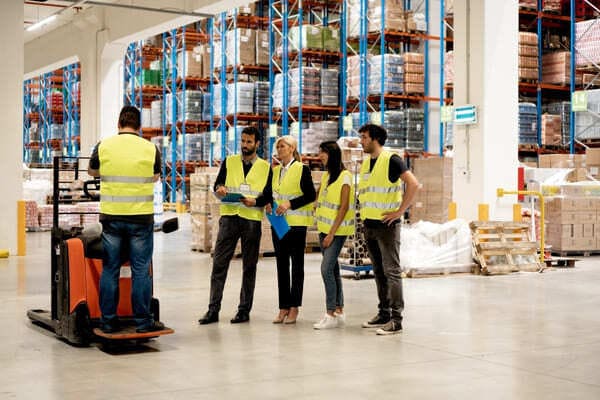 A group of warehouse workers gathered around a pallet jack