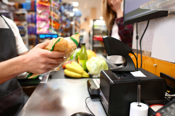 A grocery store worker ringing up an item using a presentation RF scanner