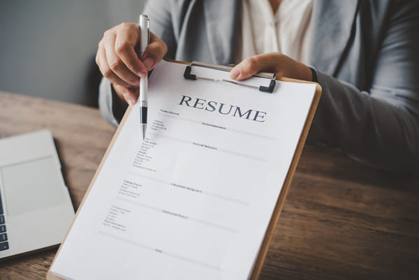 resume-on-clipboard A hiring manager handing over a clipboard with a resume on it