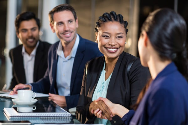 A pair of businesspeople shaking hands at a table