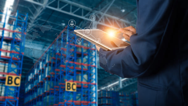 A worker standing in a warehouse tapping on a tablet screen