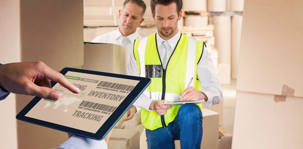 A manager using a tablet to check inventory levels in a warehouse stock room