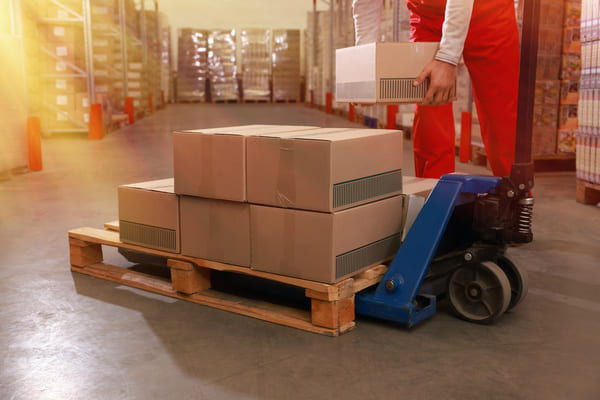 A warehouse worker placing cardboard boxes on a pallet