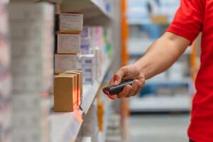 A pharmacist using a handheld RF scanner to scan a package of pills