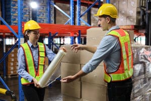 Workers shrink wrapping a pallet tight.