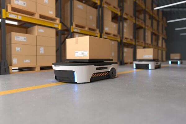 Automated carts loaded with cardboard boxes traveling in a warehouse aisle