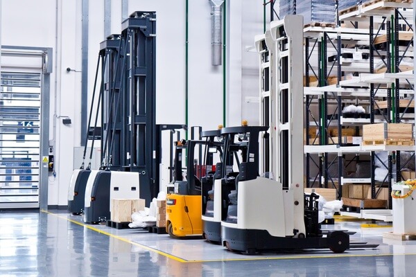 Several high-reach forklift trucks on charge in a warehouse