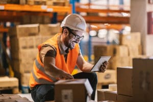 A manager using a tablet to check inventory levels in a warehouse stock room