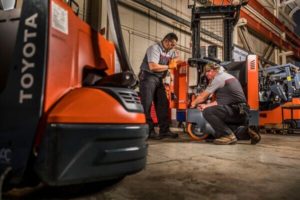 Two Toyota forklift technicians working on a reach truck