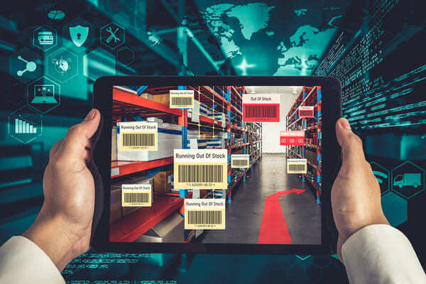 A warehouse manager viewing inventory levels on their tablet in a warehouse aisle