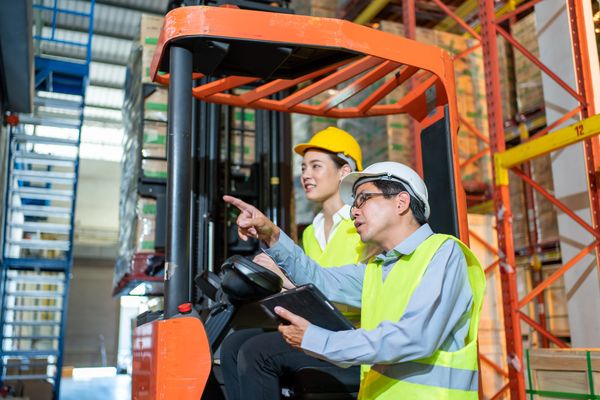 A supervisor showing a tow tractor operator how to operate the vehicle