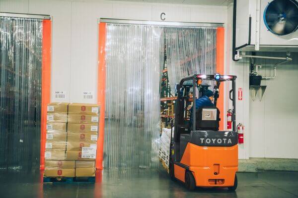 A Toyota forklift entering a cold storage holding facility with a pallet