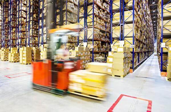 forklifts-in-busy-warehouse A forklift drives through a busy warehouse