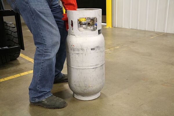 An operator preparing to lift a forklift propane tank