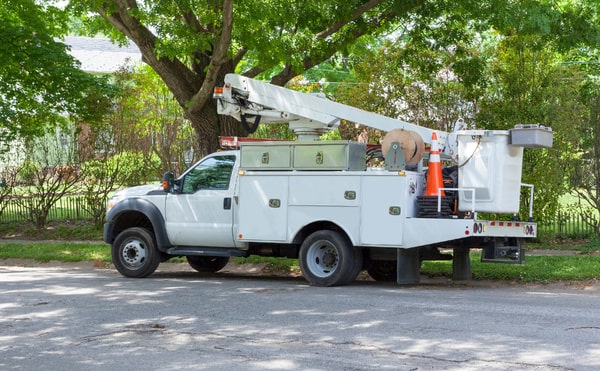 A cherry picker bucket truck parked on the side of a residential street