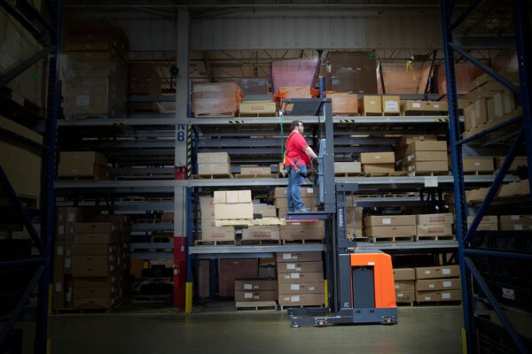 A worker on a Toyota order picker in warehouse aisle