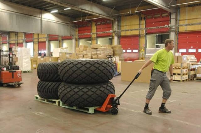 warehouse-worker-hauling-tires-on-pallets-with-Toyota-Hand-Pallet-Jack A warehouse worker hauling tires on pallets with a Toyota Hand Pallet Jack