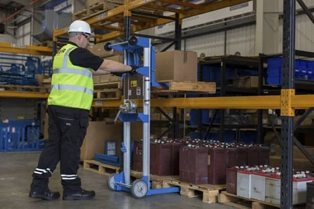 A worker using a Genie material lift to remove a pallet from racking