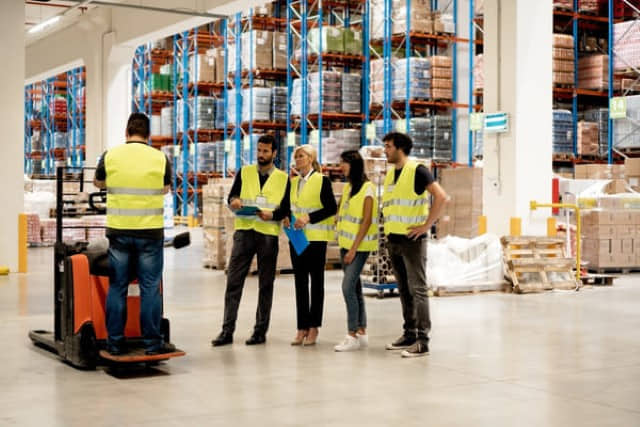 A supervisor conducting forklift training in the workplace on a pallet jack with employees